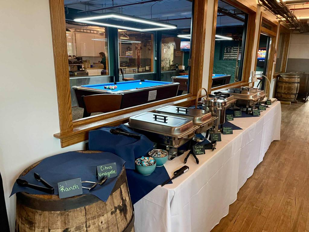 Buffet setup with chafing dishes and pool table in the background.