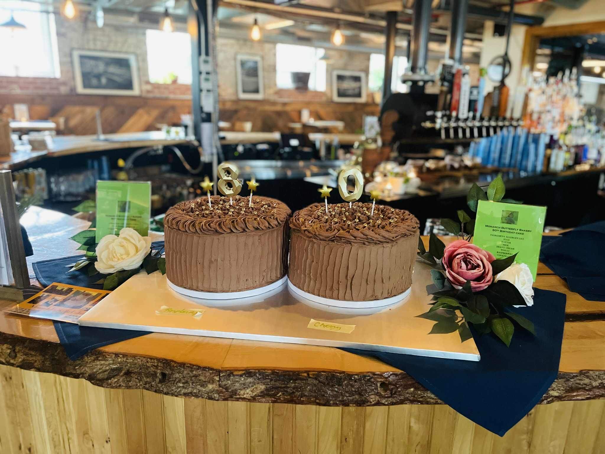 Two intricately decorated chocolate cakes on display in a cozy bakery.