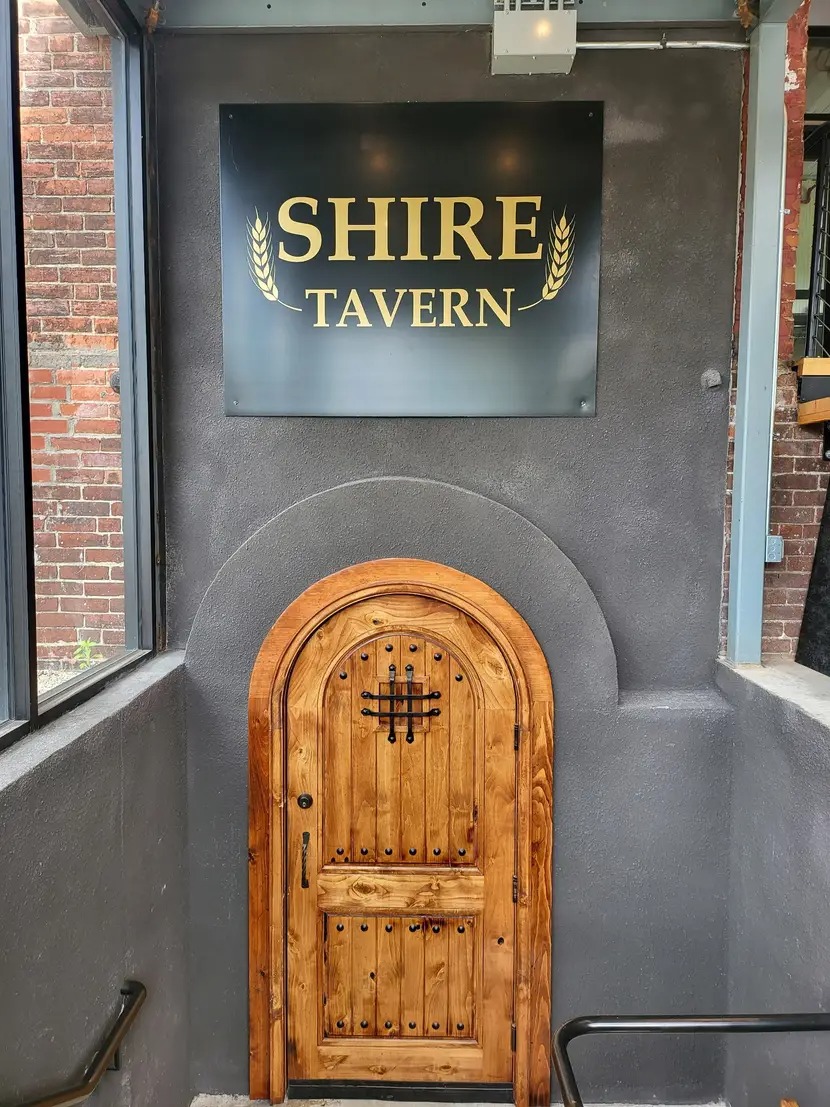 Small wooden door beneath a Shire Tavern sign.