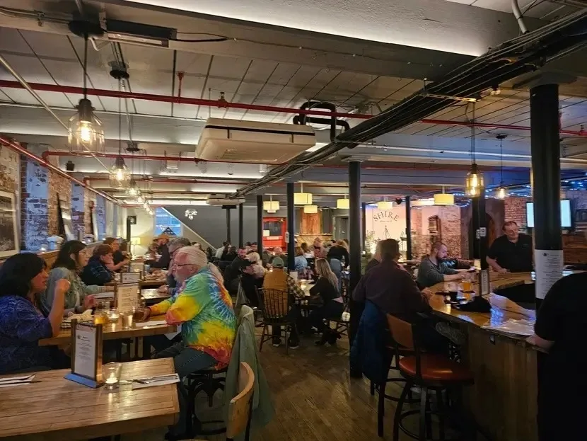 Busy bar with people socializing and colorful lighting.