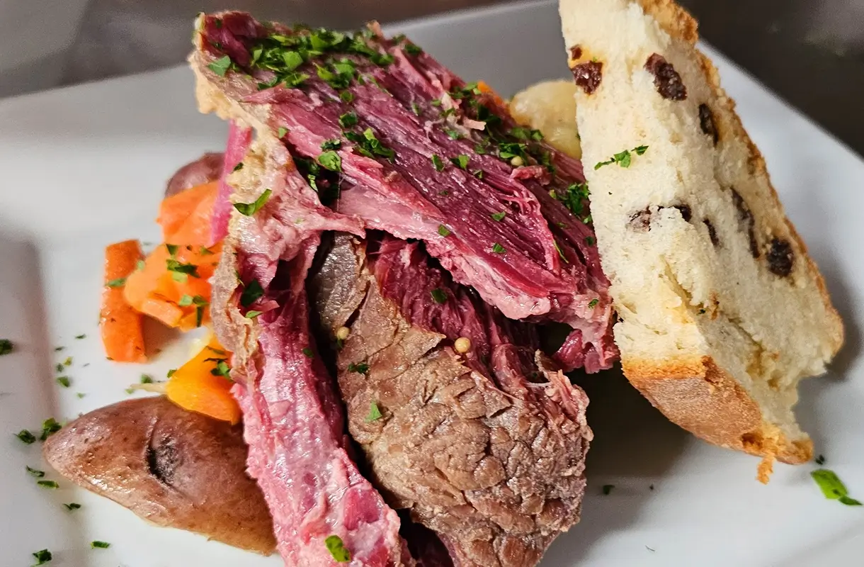 Close-up of a sliced roast beef sandwich with herbs and bread.